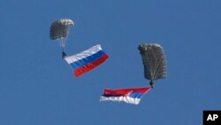 Serbian soldiers parachute from a transport helicopter with Russian, left and Serbian flags during the Russian-Serbian joint antiterrorist exercise Srem 2014, at Nikinci training ground, 60 kilometers west of Belgrade, Serbia, Nov. 14, 2014.