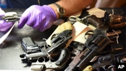 FILE - Forensic firearms examiners inspect weapons turned in by residents in a gun buy-back program co-sponsored with the New Life Covenant Church Southeast in the 6th Police District, in this June 2, 2018, photo provided by the Chicago Police Department.