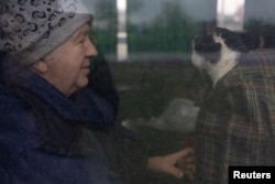 A woman who has been evacuated by the Red Cross from the Donetsk area sits with her cat after their bus stopped at a gas station on their way to Lviv, outside Dnipro, Ukraine April 21, 2022. (REUTERS/Jorge Silva)