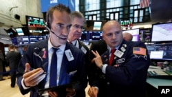 Traders Gregory Rowe, left, and Daniel Kryger, center, work with specialist Mario Picone on the floor of the New York Stock Exchange, Aug. 6, 2019. 