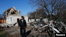 Seorang laki-laki berdiri di depan puing-puing sebuah rumah yang rusak akibat serangan senjata berat di Donetsk, Ukraina timur (6/11/2014).