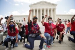 DACA recipients and their supporters take a knee in support of the Black Lives Matter movement, chanting "Say their Names" as they celebrate outside the U.S. Supreme Court after it rejected the Trump administration's atempt to end DACA.