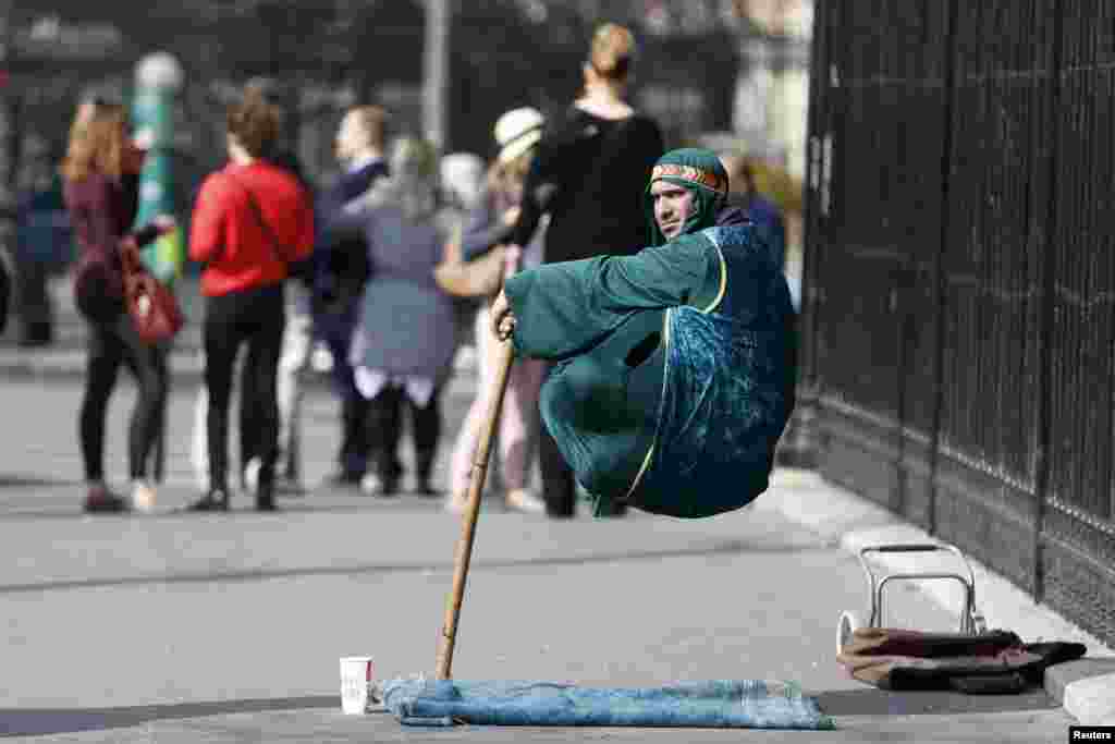 A street artist levitates in downtown Paris, France.