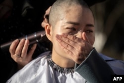 FILE - Li Wenzu has her head shaved to protest the detention of her husband and Chinese human rights lawyer Wang Quanzhang, detained during the 709 crackdown, in Beijing on Dec. 17, 2018.