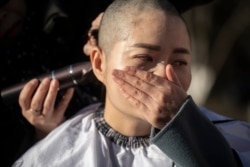 FILE - Li Wenzu has her head shaved to protest the detention of her husband and Chinese human rights lawyer Wang Quanzhang, detained during the 709 crackdown, in Beijing, Dec. 17, 2018.