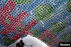 FILE - A worker stands next to an installation made of plastic bottles in Tegucigalpa March 31, 2015. The Museum of National Identity is working on installations made from recycled plastic bottles as a way to encourage recycling in the community, local media rep