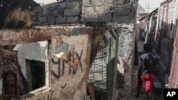 FILE - A person walks past a house that was set ablaze during a gang attack in the Post Marchand neighborhood of Port-au-Prince, Haiti, Dec. 10, 2024.