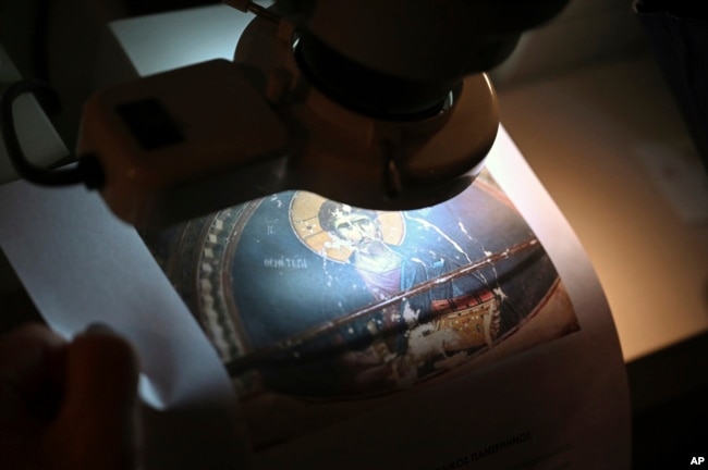 Christina Sotirakoglou a handwriting expert, observes Byzantine paintings based on photographs prints, at her office, in Thessaloniki, northern Greece, Saturday, Nov. 30, 2024. (AP Photo/Giannis Papanikos)