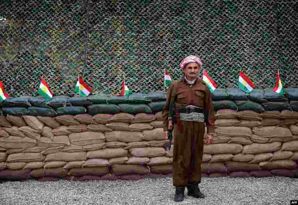 A Kurdish Peshmerga fighter stands in front of a line of Kurdish flags at a position on the frontline in the Gwer district, 40 kilometers south of Arbil, the capital of the Kurdish autonomous region in northern Iraq, as they continue to battle Islamic State (IS) group fighters.