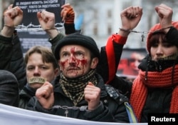 Pro-European integration supporters with taped mouths attend a rally against newly approved laws near the presidential administration in Kyiv, Ukraine, Jan. 17, 2014.