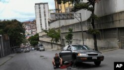 Un hombre se sienta en medio de la carretera junto a su automóvil averiado en el barrio de Petare, Caracas, Venezuela. Febrero 6, 2021.