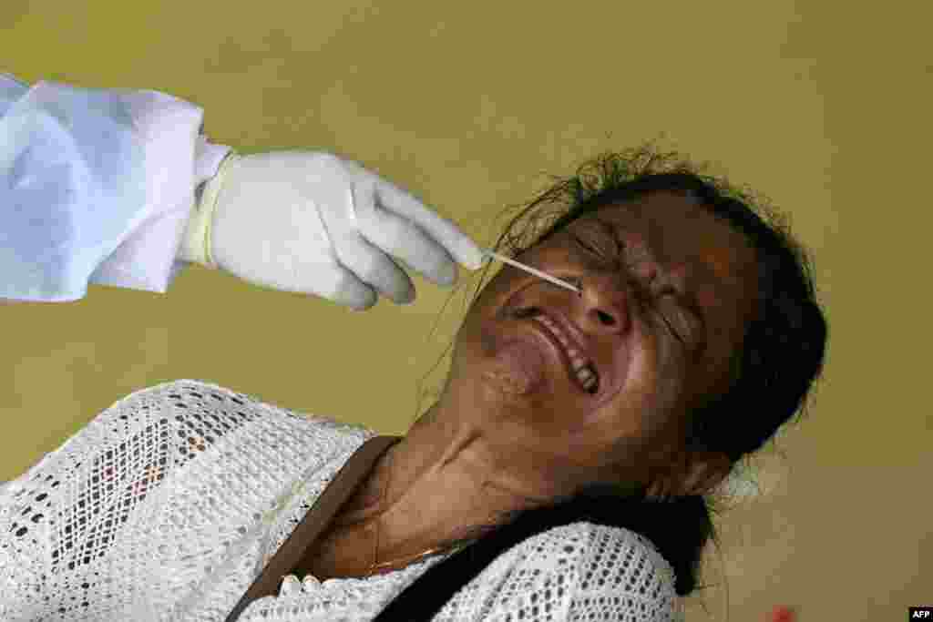 Seorang perempuan bereaksi ketika petugas kesehatan mengumpulkan sampel swab untuk tes COVID-19 di Kolombo, Sri Lanka. (Foto: AFP)