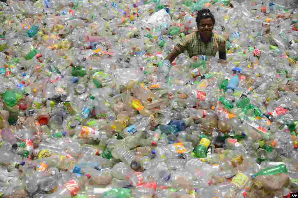 Hindistan&#39;da bir işçi, plastik şişeleri tasnif ediyor.