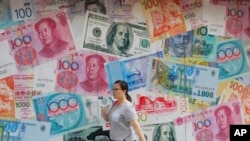 FILE - A woman walks by a money exchange shop decorated with different countries currency banknotes at Central, a business district in Hong Kong, Aug. 6, 2019.
