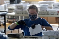 Board of election worker John Carlino opens a ballot at the warehouse where the ballots are counted for the Cuyahoga County Board of Elections, Tuesday, April 28, 2020, in Cleveland, Ohio. (AP Photo/Tony Dejak)