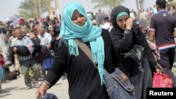 Displaced Sunni women fleeing the violence in Ramadi, carry bags as they walk on the outskirts of Baghdad, May 24, 2015. 