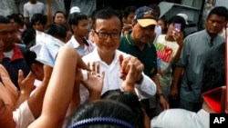 Sam Rainsy, center, leader of Cambodia National Rescue Party greets villagers while visiting a polling station at Chak Angre Leu pagoda, in Phnom Penh, Cambodia, Sunday, July 28, 2013.