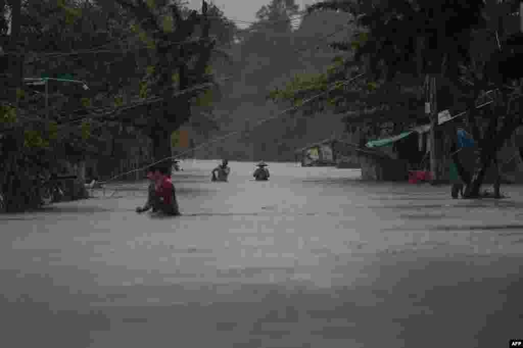 Warga berjalan melewati jalanan yang tergenang banjir di Mawlamyine, Myanmar.