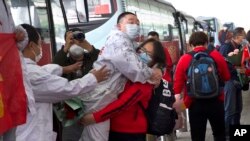 A medical worker from China's Jilin Province, in red, embraces a colleague from Wuhan as she prepares to return home at Wuhan Tianhe International Airport in Wuhan in central China's Hubei Province, Wednesday, April 8, 2020. (AP Photo/Ng Han Guan)