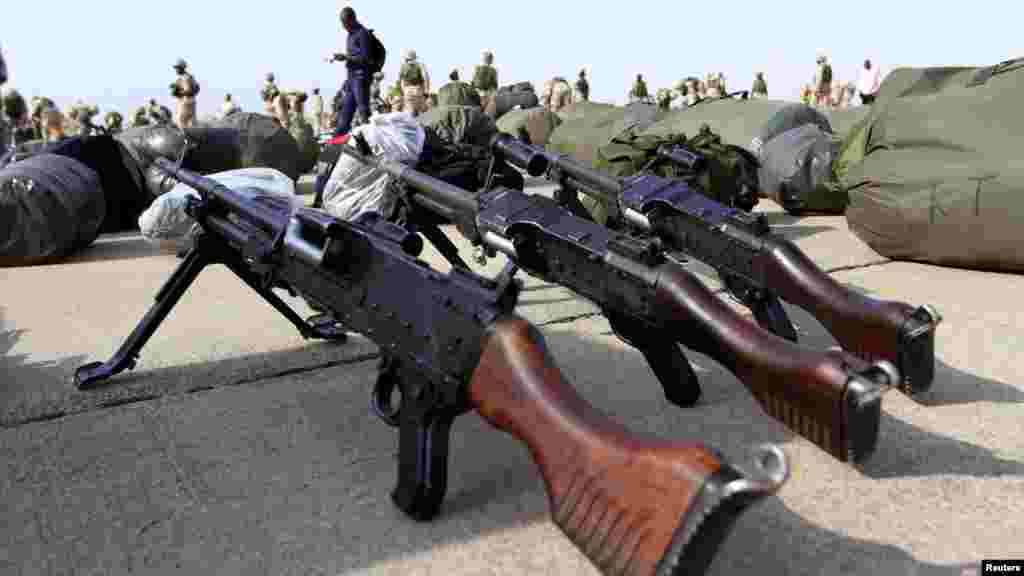 Guns are arranged on the ground as Nigerian soldiers prepare to board a military plane before leaving for Mali.