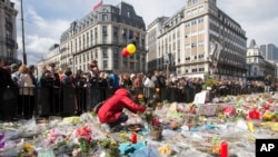 A woman lays flowers on a memorial to victims of the Brussels attacks during a march against hate in Brussels on Sunday, April 17, 2016.