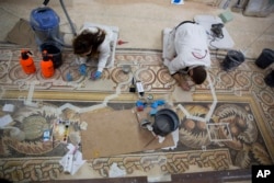 In this Thursday, Dec. 6, 2018 photo, restoration experts work on a mosaic inside the Church of the Nativity, built atop the site where Christians believe Jesus Christ was born, in the West Bank City of Bethlehem. (AP Photo/Majdi Mohammed)