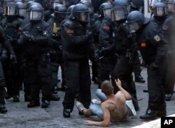 A man, sitting on the ground, gestures as police officers approach during a protest against the G-20 summit in Hamburg, Germany, July 7, 2017.