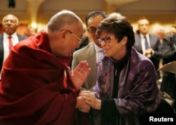 The Dalai Lama shakes hands with Valerie Jarrett, senior advisor to U.S. President Barack Obama, at the National Prayer Breakfast in Washington, Feb. 5, 2014.
