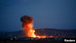 Asap dan api di atas kota Kobani akibat serangan udara, terlihat dari tempat penyeberangan perbatasan Turki-Suriah, Mursitpinar di kota Suruc, provinsi Sanliurfa, 18 Oktober 2014. 