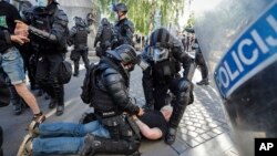 FILE - A protester is detained by riot police during an anti-government demonstration in Ljubljana, Slovenia, June 25, 2021. 