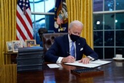 El presidente Joe Biden firma su primera orden ejecutiva en la Oficina Oval de la Casa Blanca, en Washington, el miércoles 20 de enero de 2021.