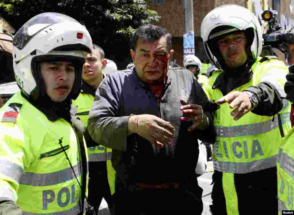 Un herido es auxiliado por policías colombianos, luego de un atentado en el distrito comercial de la capital.