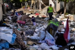 A Hezbollah paramedic walks between debris after an airstrike hit an apartment in a multistory building in Beirut, Lebanon, Oct. 3, 2024.