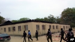 FILE—Security walk past the burned government secondary school Chibok, where gunmen abducted more than 200 students, April, 21. 2014, in Chibok, Nigeria.