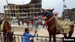 A man holds a horse near damaged buildings during the first day of the Muslim holiday of Eid al-Fitr in Raqqa, Syria, June 5, 2019. 