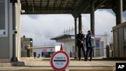 FILE - Kosovo police officers stand at the closed Merdare border crossing between Kosovo and Serbia, Dec. 28, 2022. 