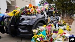 La patrulla policial estacionada afuera del Departamento de Policía de Boulder cubierta con ramos de flores en homenaje después de que un oficial fuera una de las víctimas de un tiroteo masivo en una tienda de comestibles el martes 23 de marzo de 2021.