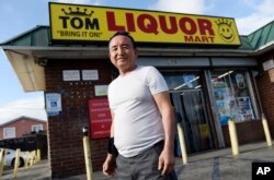 James Oh, owner of Tom's Liquors, poses outside his store at the intersection of Florence and Normandie, April 18, 2017, in Los Angeles.