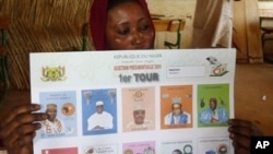 A woman holds a ballot paper bearing portraits of the presidential candidates at a polling station, in Niamey, January 31, 2011.