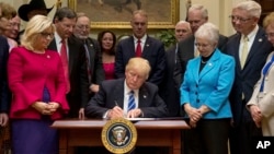 President Donald Trump signs one of various bills in the Roosevelt Room of the White House in Washington, March 27, 2017.