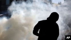 Anti-government protester runs from tear gas fired by riot police in A'ali, Bahrain, November 23, 2011.