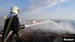 A fireman douses burned tents in a camp for internally displaced people near Sarmada in Syria's Idlib province in this undated still image taken from video on May 6, 2016.