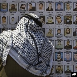 A Palestinian man looks at pictures of Palestinians imprisoned in Israeli jails, Thursday, April 15, 2010. Palestinians marked the annual prisoner's day by calling for the release of over 11,000 Palestinian prisoners, including women and children, curre