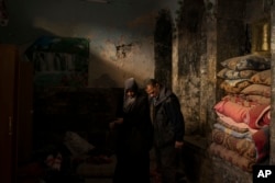 FILE - Yahya Ali, right, and Haifa Shehab, look through the rubble in their house, in the Old City of Mosul, Iraq, Nov. 16, 2017.