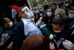 Seorang demonstran, mengenakan masker untuk melindungi diri terhadap virus corona, memberi isyarat saat didorong ke mobil polisi setelah ditangkap ketika berunjuk rasa dalam peringatan Hari Buruh di Istanbul, Jumat, 1 Mei 2020.