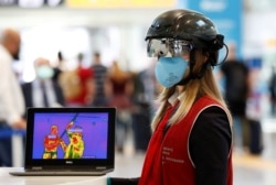 Seorang petugas mengenakan "helm pintar" untuk memindai suhu para penumpang di Bandara Fiumicino, Italia, di tengah pandemi COVID-19. (Foto: Reuters)