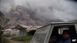 Residents ride in a truck as Mount Sinabung releases pyroclastic flows during its eruption in Karo, North Sumatra, Indonesia, Aug. 2, 2017.