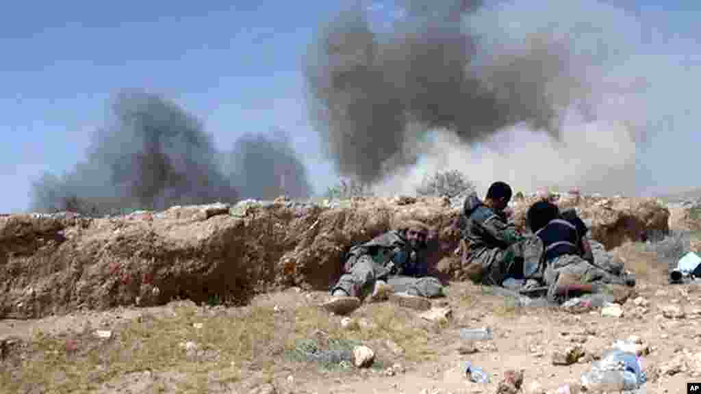 In this picture released on Wednesday, May 20, 2015 by the website of Islamic State militants, Islamic State fighters take cover during a battle against Syrian government forces on a road between Homs and Palmyra, Syria.