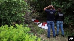 Investigators look at human remains placed in red evidence bags, dug from a clandestine grave site in Arbolillo, Veracruz state, Mexico, Sept. 7, 2018.