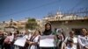 Displaced Syrians from the northern city of Afrin, hold placards during a demonstration to condemn violations by local Turkish-backed factions in front of the UN office in the northern Kurdish Syrian city of Qamishli on June 1, 2020.